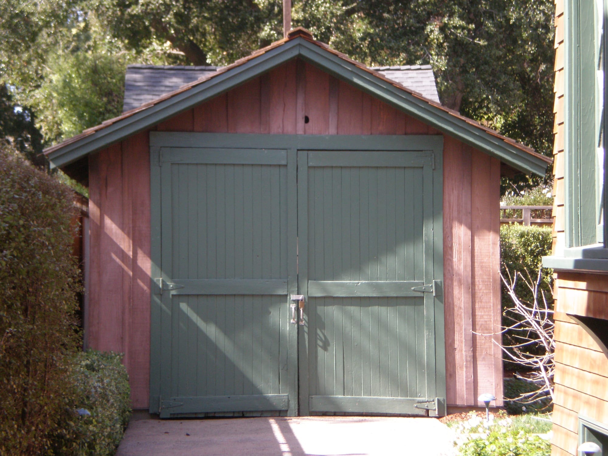 A scrappy red garage with green doors. 